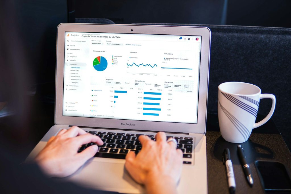 working on computer analyzing data with coffee mug and pens on desk