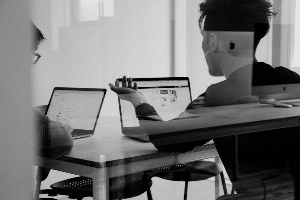 two men using laptops in professional setting