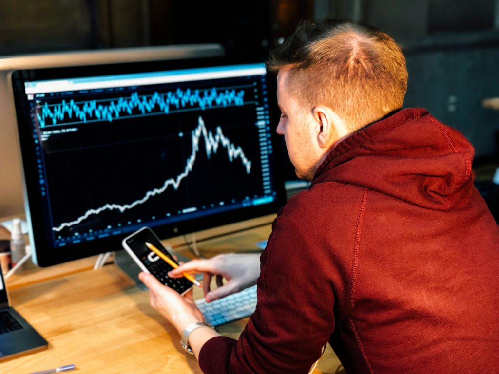 A man analyzing data on his computer and phone.