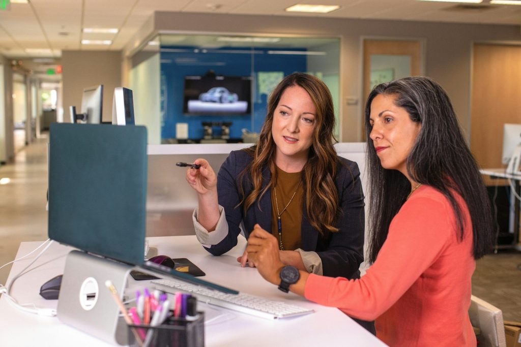 two professionals discussing visuals on laptop screen at work