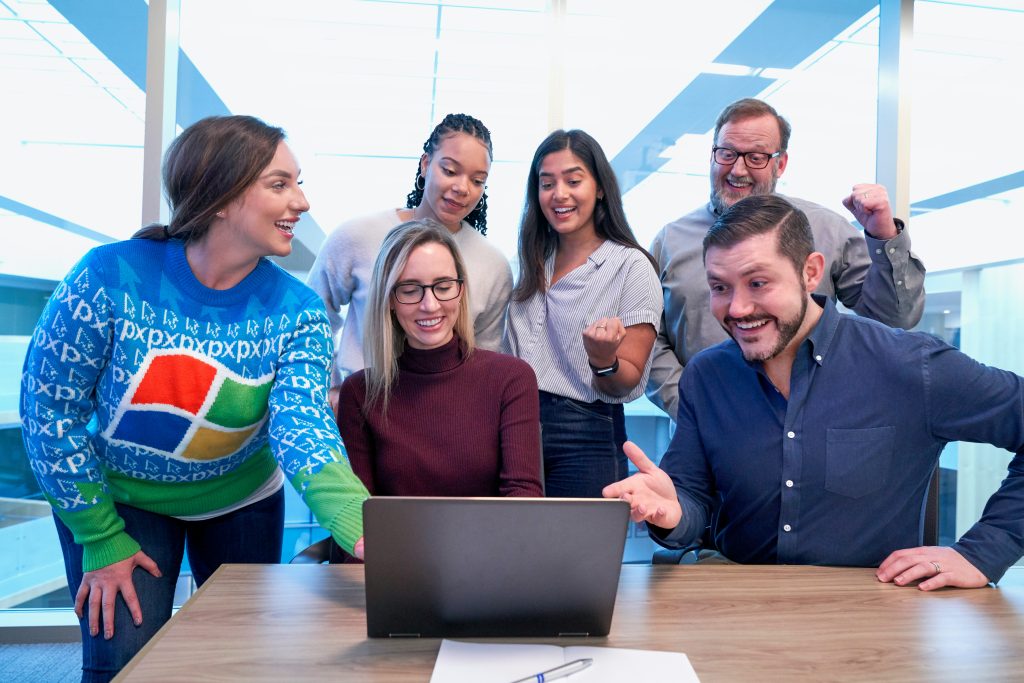 Group of colleagues engaging together around a laptop