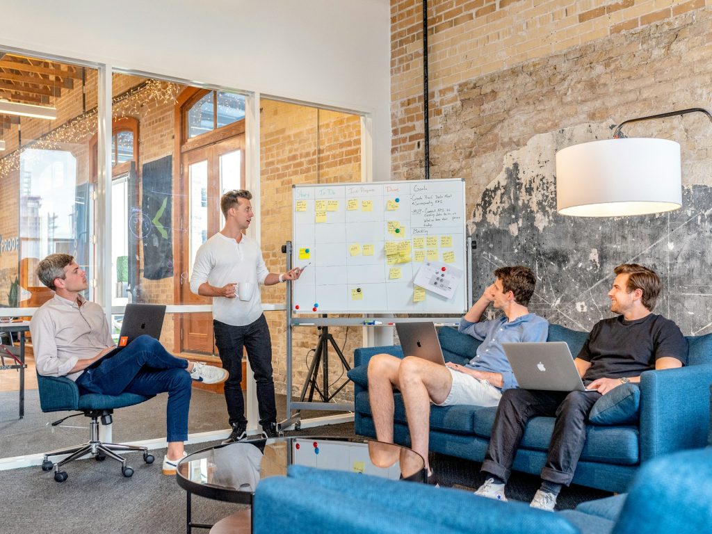 three men watching as another man leads a presentation on a whiteboard